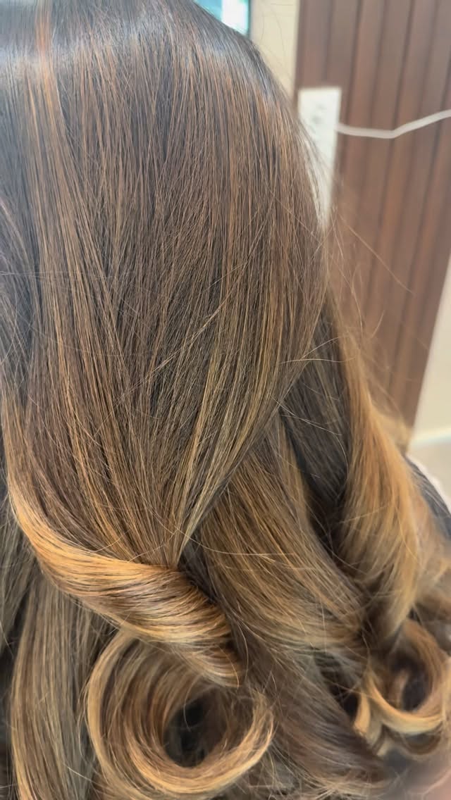 Glänzende Balayage-Locken in warmem Karamellton, gestylt bei The Three Hairdesign in Wien