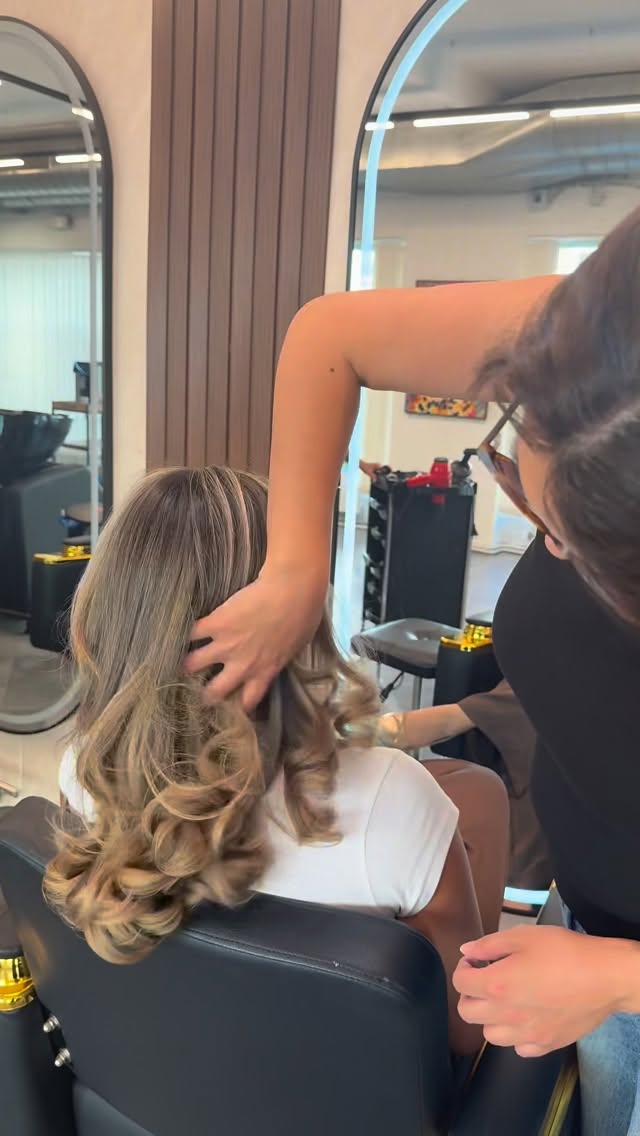 Voluminöse Blow-out-Locken werden im Salon in Form gebracht
